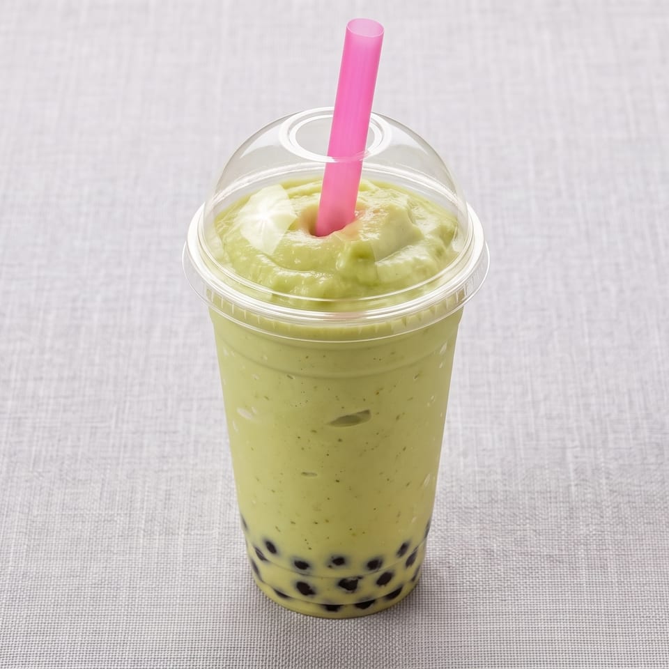 Green matcha bubble tea with tapioca pearls, whipped topping, and a pink straw in a clear cup.